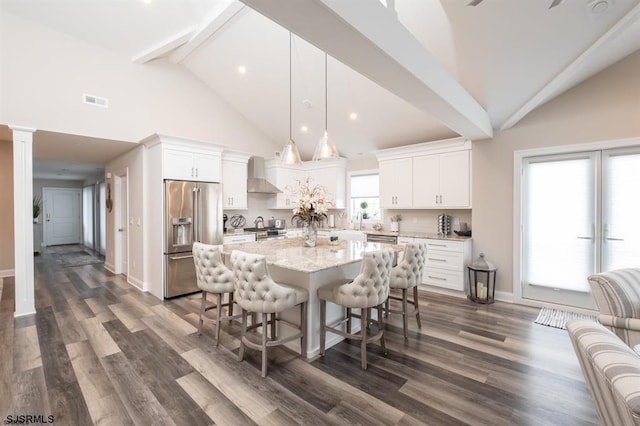 kitchen featuring white cabinetry, appliances with stainless steel finishes, a kitchen island, pendant lighting, and wall chimney range hood