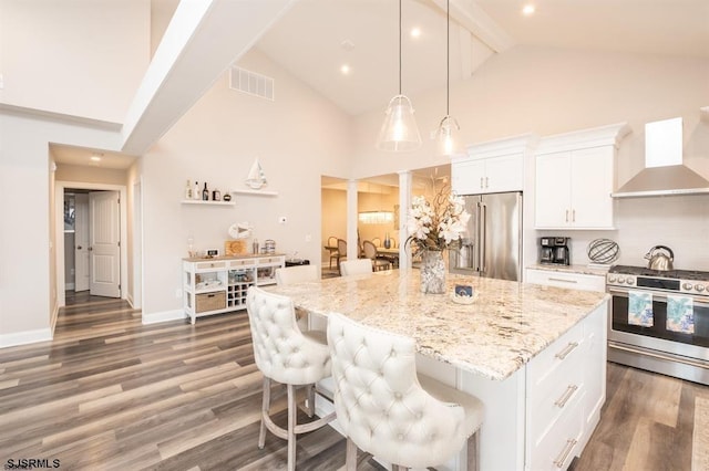 kitchen featuring a spacious island, wall chimney exhaust hood, white cabinetry, pendant lighting, and stainless steel appliances