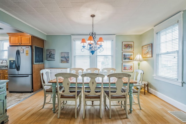 dining area featuring a notable chandelier, plenty of natural light, light wood-type flooring, and crown molding