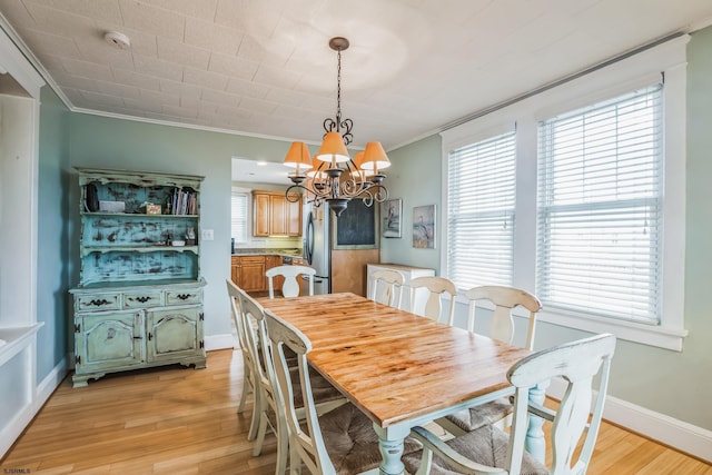 dining space featuring light hardwood / wood-style flooring, a notable chandelier, and crown molding