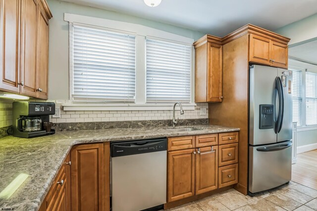 kitchen featuring light stone countertops, appliances with stainless steel finishes, tasteful backsplash, and sink