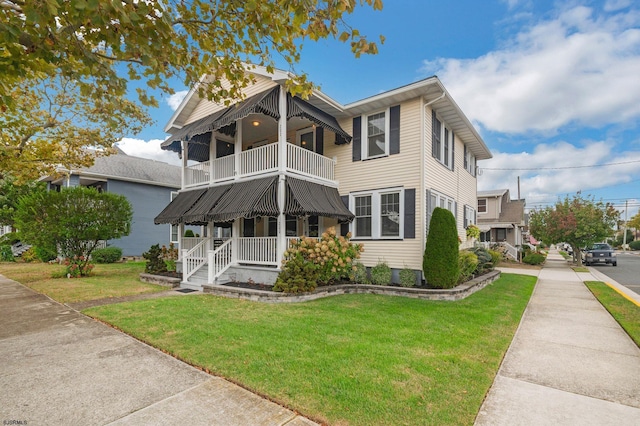 view of front facade with a balcony, covered porch, and a front yard