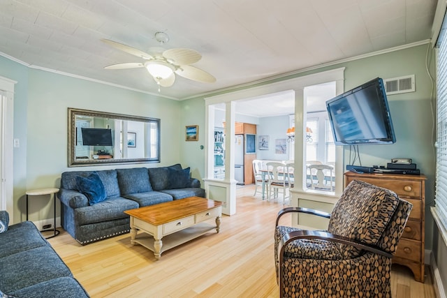 living room featuring ceiling fan, wood-type flooring, crown molding, and decorative columns