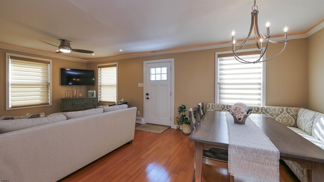 dining space with ceiling fan with notable chandelier, hardwood / wood-style flooring, and crown molding