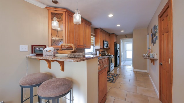 kitchen featuring kitchen peninsula, a kitchen breakfast bar, appliances with stainless steel finishes, and pendant lighting