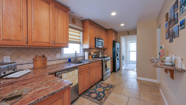 kitchen featuring light tile patterned floors, sink, stainless steel appliances, and dark stone countertops