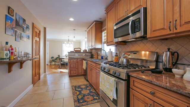 kitchen featuring stainless steel appliances, light tile patterned floors, decorative light fixtures, dark stone countertops, and a chandelier