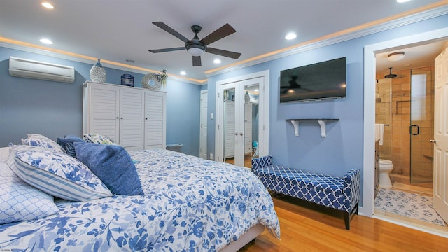 bedroom featuring a wall mounted air conditioner, french doors, ceiling fan, wood-type flooring, and connected bathroom