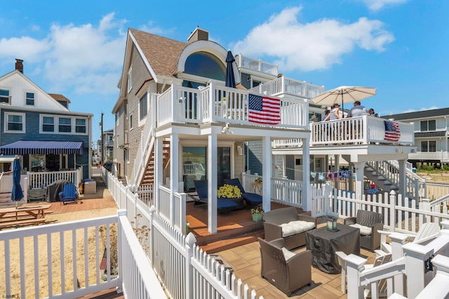 back of property with an outdoor hangout area, a balcony, and a deck