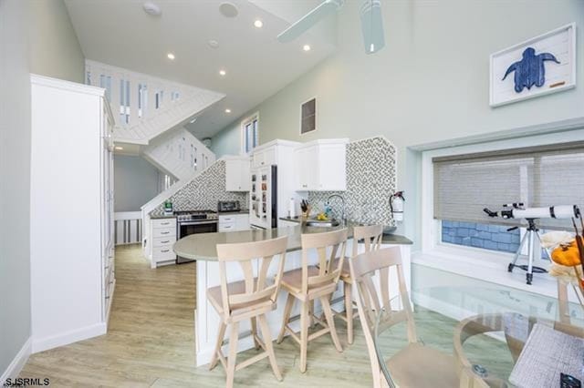 kitchen featuring backsplash, refrigerator, stainless steel range oven, and white cabinets