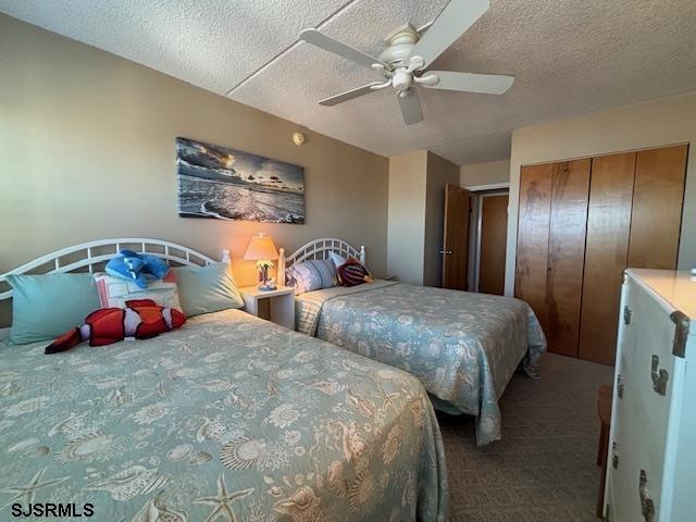 carpeted bedroom with a textured ceiling, a closet, and a ceiling fan