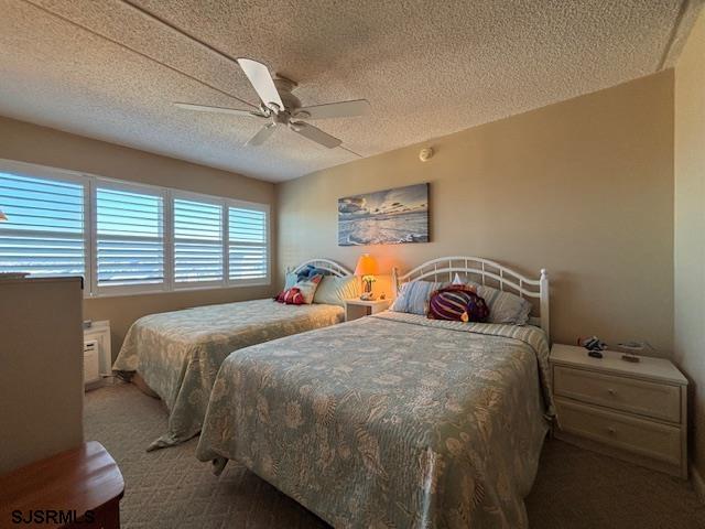 carpeted bedroom featuring ceiling fan and a textured ceiling