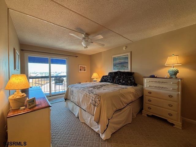 carpeted bedroom featuring access to exterior, a ceiling fan, and a textured ceiling