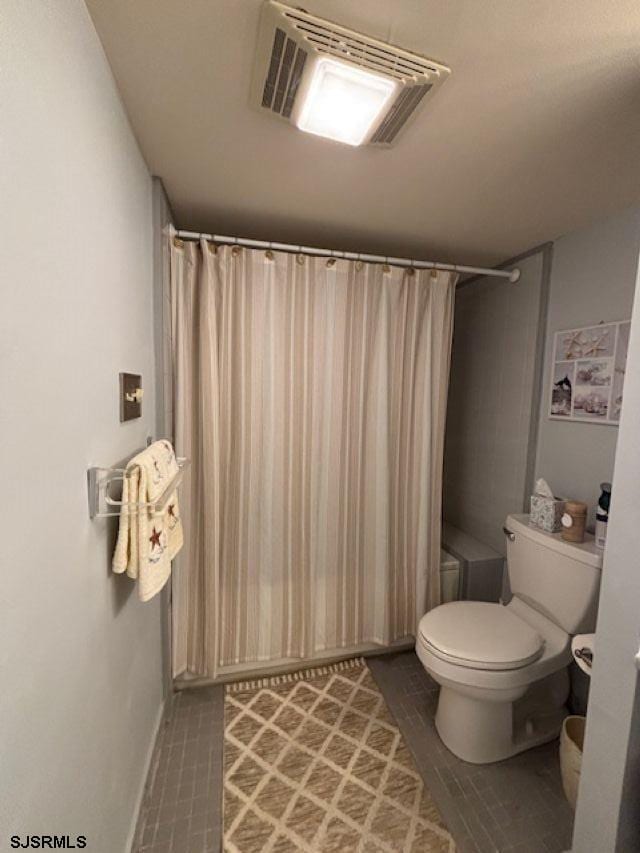 bathroom with shower / tub combo, baseboards, visible vents, and toilet