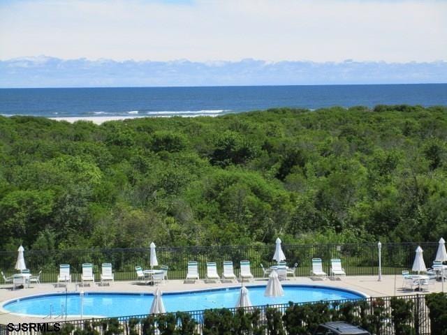 exterior space featuring a water view, a swimming pool, fence, and a patio