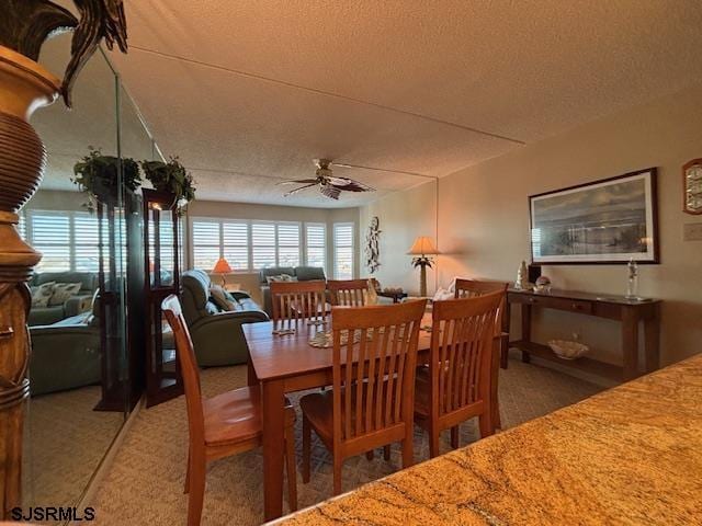 dining space featuring carpet flooring, ceiling fan, and a textured ceiling