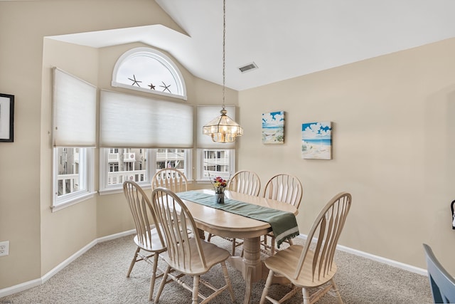 carpeted dining room with lofted ceiling and an inviting chandelier