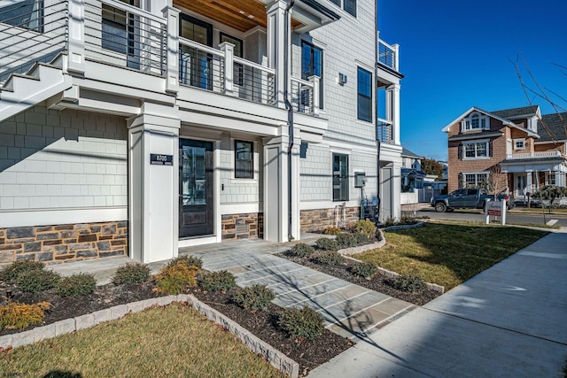 doorway to property featuring a lawn and a balcony