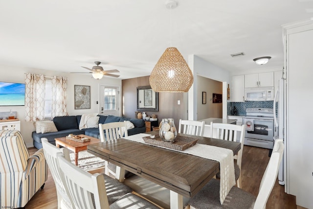 dining room with ceiling fan and dark wood-type flooring