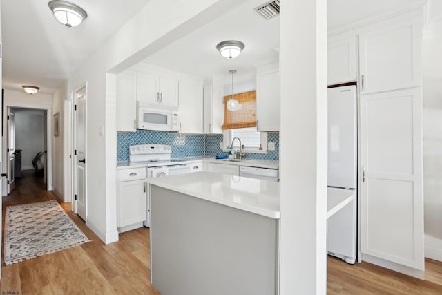 kitchen featuring pendant lighting, white appliances, white cabinets, decorative backsplash, and light hardwood / wood-style floors