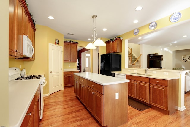 kitchen featuring white appliances, sink, hanging light fixtures, a kitchen island, and light hardwood / wood-style floors