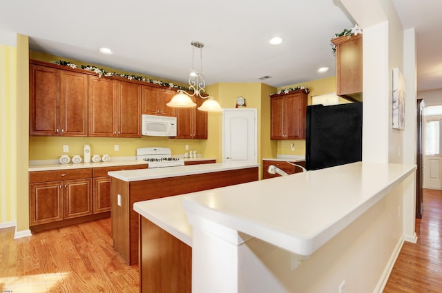 kitchen with a chandelier, light hardwood / wood-style flooring, pendant lighting, and white appliances