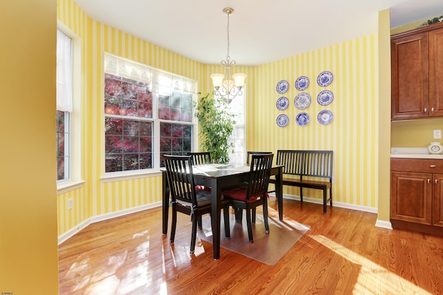 dining space with light hardwood / wood-style flooring and a chandelier