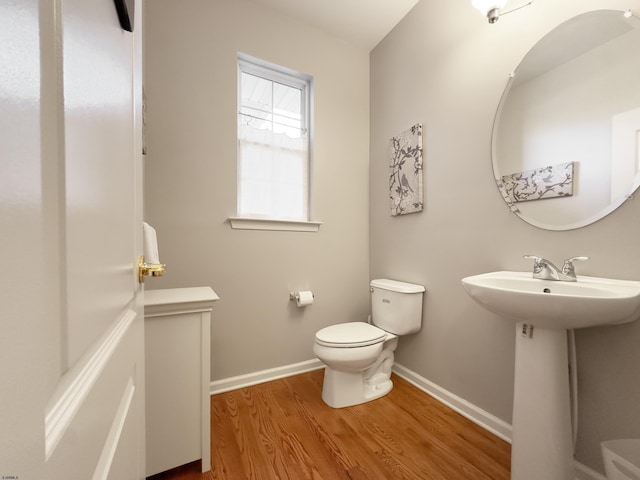 bathroom with wood-type flooring, toilet, and sink