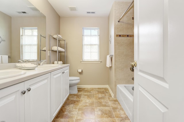 full bathroom featuring a wealth of natural light, vanity, tiled shower / bath combo, and toilet