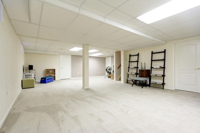 basement featuring a paneled ceiling and light colored carpet