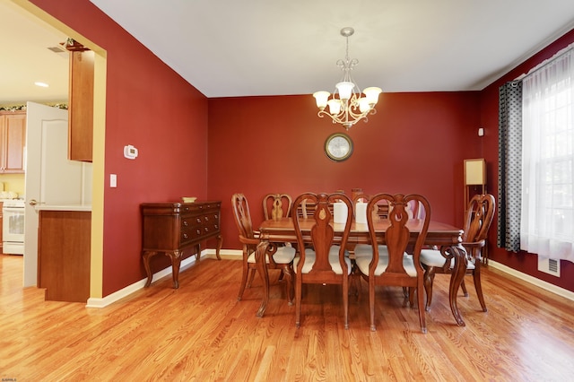 dining space with light hardwood / wood-style floors and a chandelier