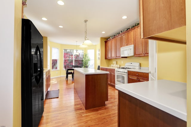 kitchen featuring decorative light fixtures, white appliances, a center island, and light hardwood / wood-style floors