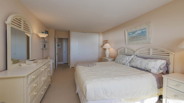 bedroom with a textured ceiling, light carpet, and a closet