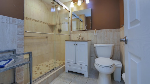 bathroom featuring tile patterned floors, an enclosed shower, toilet, vanity, and tile walls