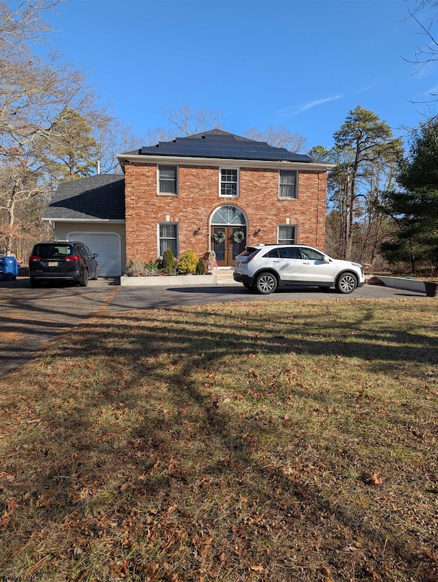 back of property featuring solar panels, a garage, and a yard