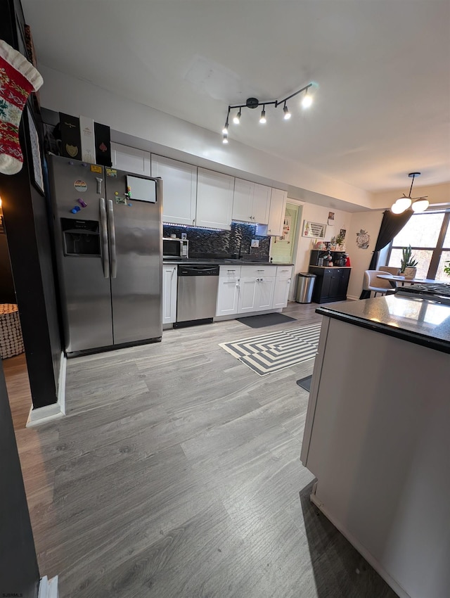 kitchen with tasteful backsplash, white cabinetry, light hardwood / wood-style flooring, and appliances with stainless steel finishes