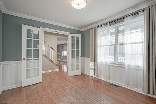 unfurnished room with light hardwood / wood-style floors, ornamental molding, and french doors