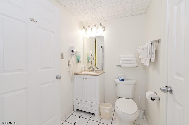 bathroom with tile patterned flooring, vanity, toilet, and a drop ceiling