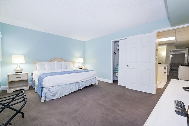 bedroom featuring dark carpet, a walk in closet, a textured ceiling, and a closet