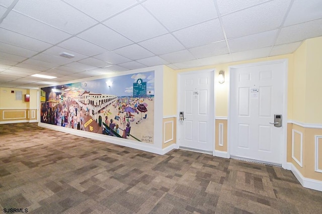 interior space featuring dark carpet and a drop ceiling