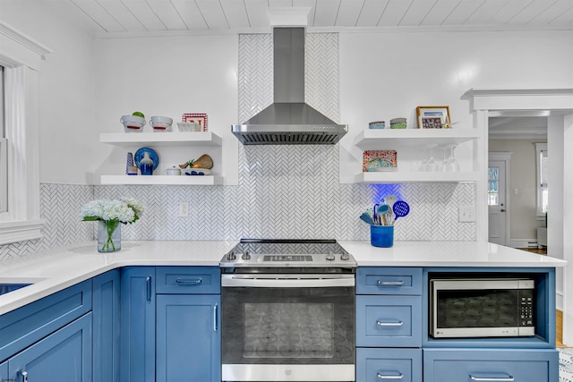 kitchen with decorative backsplash, wall chimney range hood, blue cabinetry, and appliances with stainless steel finishes