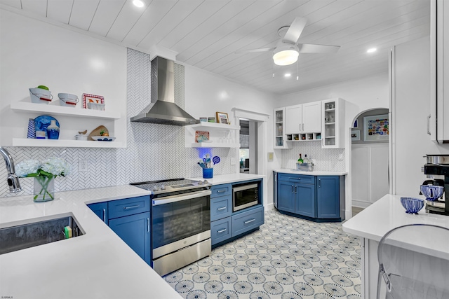 kitchen featuring blue cabinetry, backsplash, wall chimney exhaust hood, and appliances with stainless steel finishes