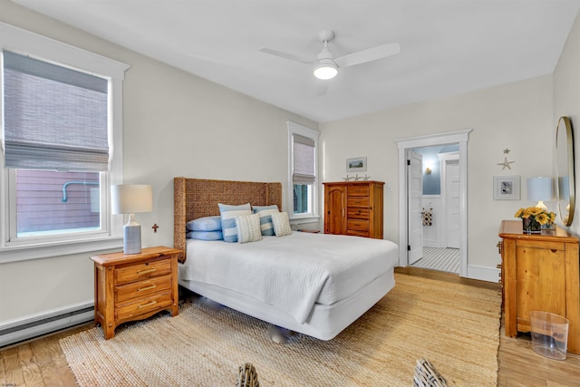 bedroom with ceiling fan, light wood-type flooring, and a baseboard heating unit