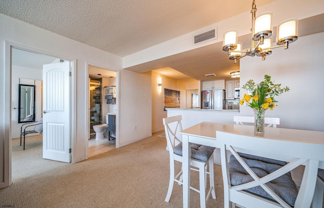 dining space featuring a chandelier, light colored carpet, and a textured ceiling