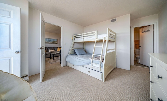 carpeted bedroom featuring a textured ceiling, a baseboard radiator, and ensuite bath