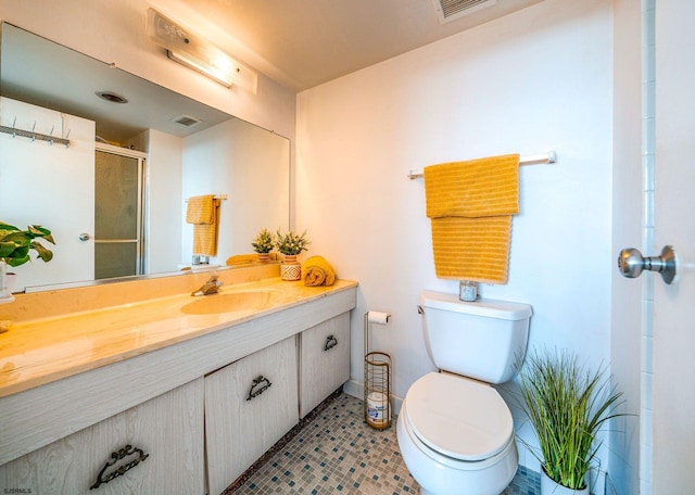 bathroom featuring tile patterned floors, vanity, toilet, and a shower with shower door