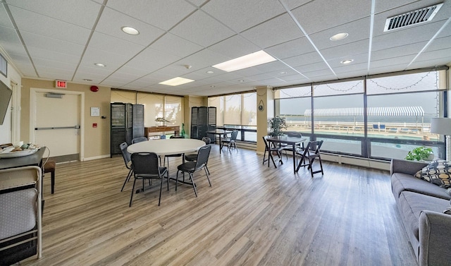 dining space with a paneled ceiling, plenty of natural light, and hardwood / wood-style floors