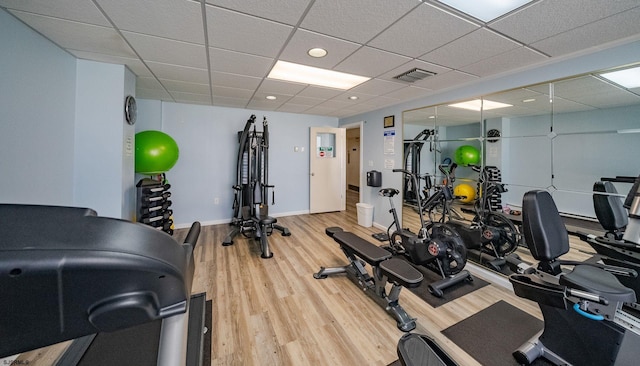 workout area with wood-type flooring and a paneled ceiling