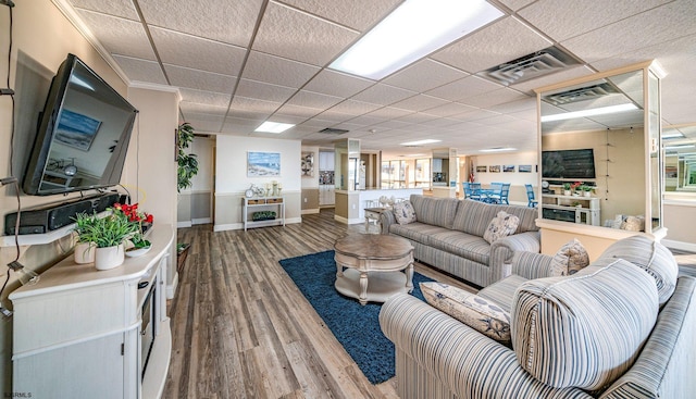 living room with hardwood / wood-style floors, a drop ceiling, and crown molding