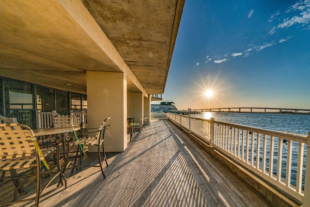 deck at dusk featuring a water view